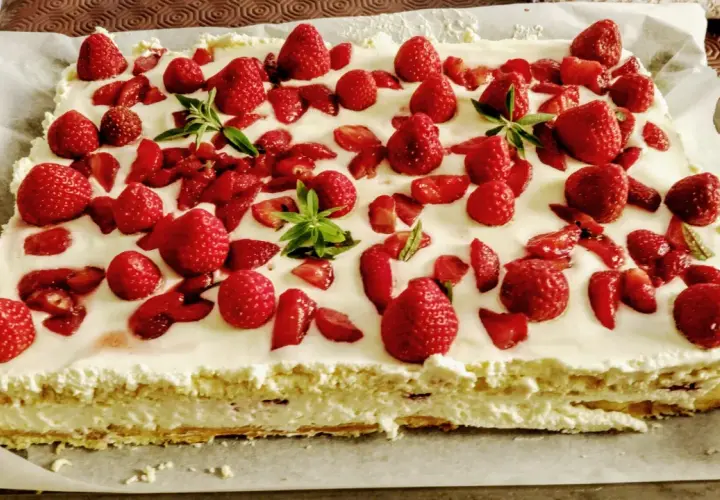 Un délicieux entremet fraise, garni de fruits rouges frais et de feuilles de menthe, sur une base crémeuse.
