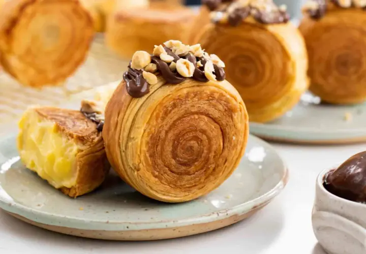 Deliziosi dolci francesi, croissant a spirale ripieni di crema e guarniti con cioccolato e nocciole.
