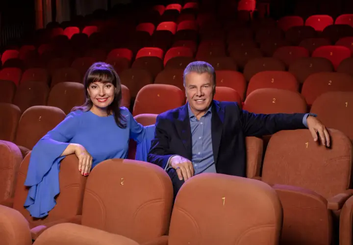 Uśmiechnięci aktorzy w Teatrze Kamienica, siedzący w rzędzie pomarańczowych foteli.