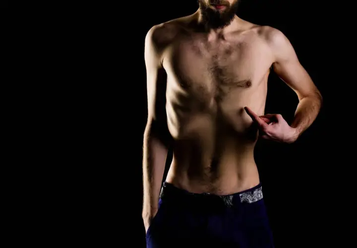 Mężczyzna z brodą wskazuje na swoje żebra, zastanawiając się, czemu nie mogę przytyć.