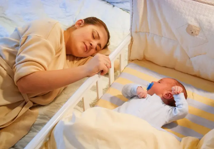 Mamma dorme accanto al lettino dove un bambino di 2 anni si sveglia piangendo disperato.
