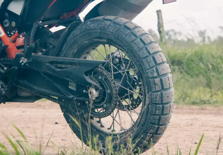 Tylne koło motocykla z oponą Pirelli Scorpion Rally STR na szutrowej drodze, gotowe na przygodę.