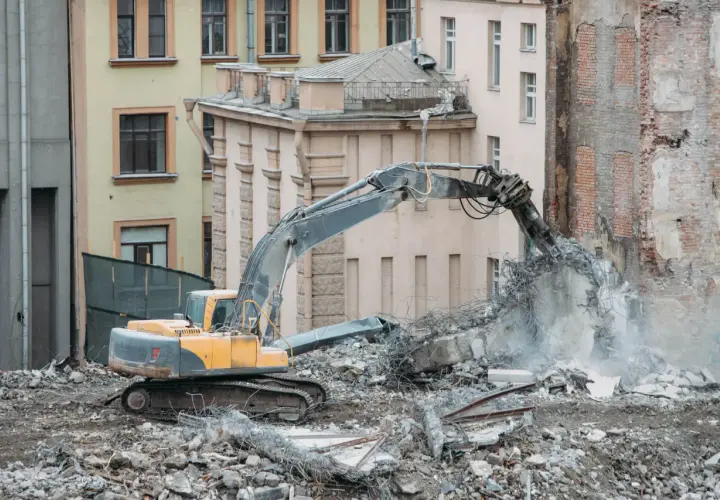 Koparka niszczy budynek do rozbiórki. Co z lokatorami? Gruz i pył unoszą się w powietrzu.
