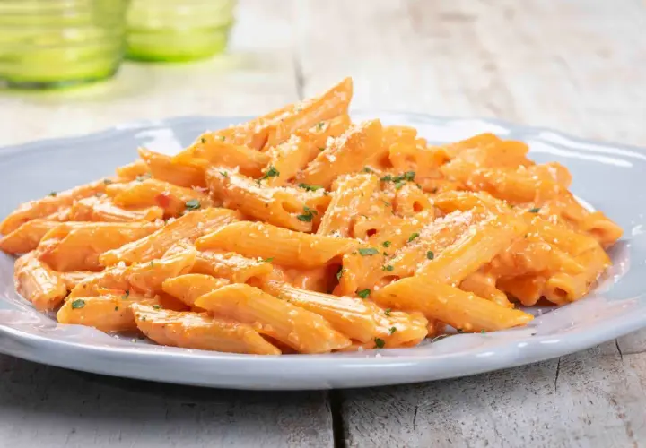 Penne cremose con salsa rosa, un piatto gustoso e paste facili da fare, guarnito con parmigiano e prezzemolo.