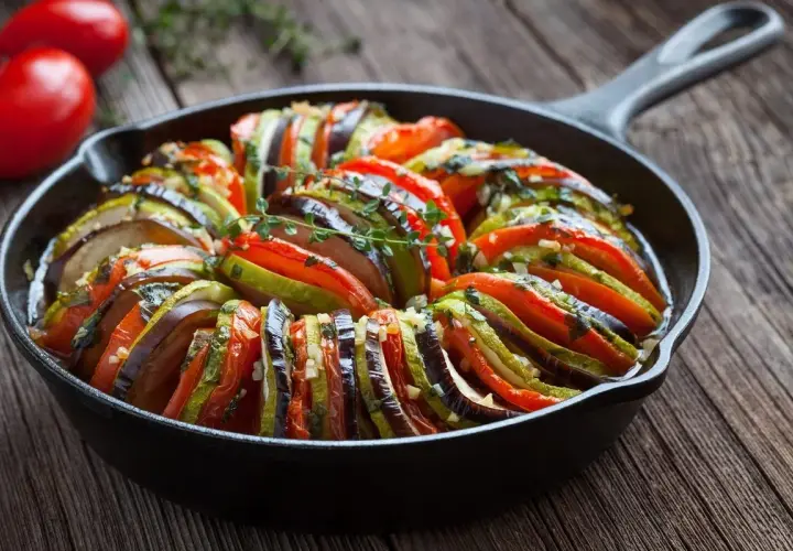 Ratatouille w naczyniu żeliwnym, idealne danie, by dowiedzieć się, co zjeść we Francji. Aromatyczne warzywa zapiekane z ziołami.
