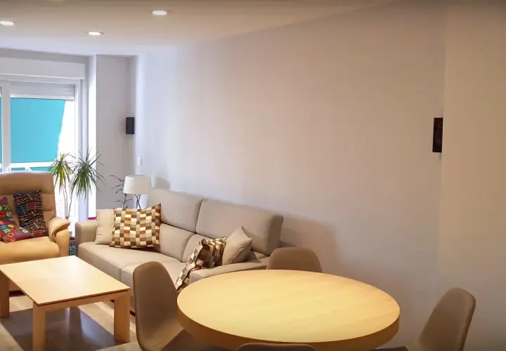 Salón moderno con sofá beige, mesa de centro y mesa redonda. El **IP40 significado** se refleja en la iluminación empotrada y el diseño funcional.