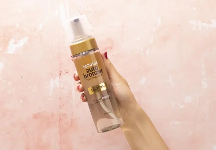 Mano sostiene botella de mousse autobronceador Deliplus de Mercadona. Bronceado natural y uniforme.