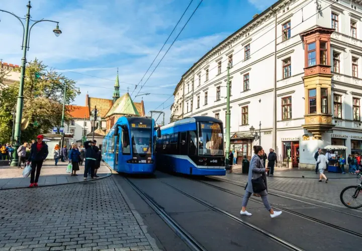 Kraków: dwa niebieskie tramwaje na ulicy, ludzie czekają na przystanku. Idealne na bilet godzinny Kraków.