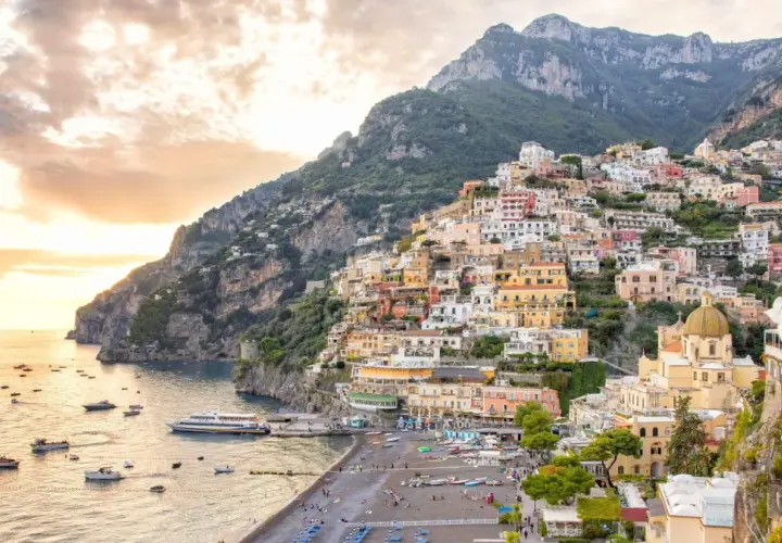 A stunning view of Positano, perfect for your Amalfi Coast 2-day itinerary. Colorful houses cascade down a steep cliff to a beach dotted with boats.