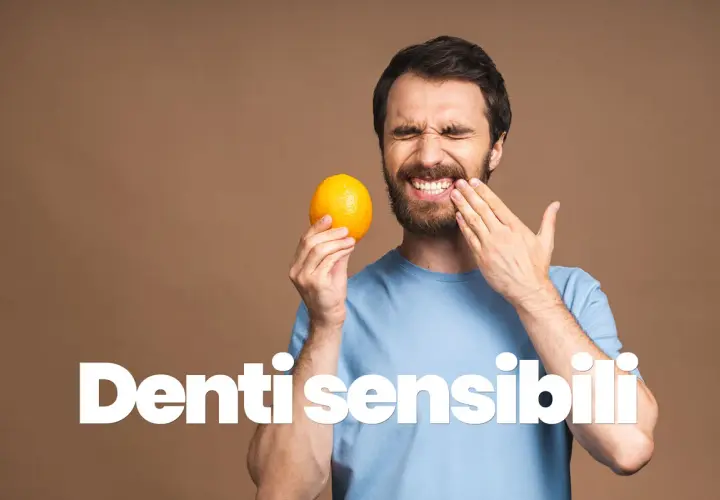 Uomo con espressione di dolore, tiene un'arancia e si tocca la guancia, soffre di sensibilità dentale.