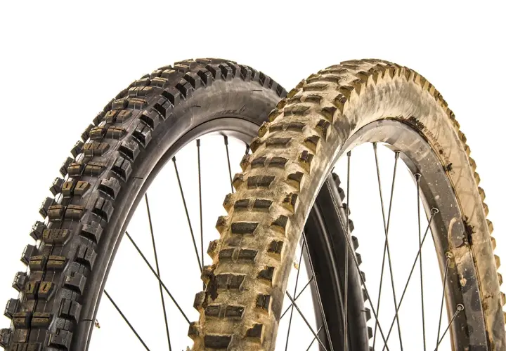 Two mountain bike tires, one new and one worn, illustrate when to replace mountain bike tires.