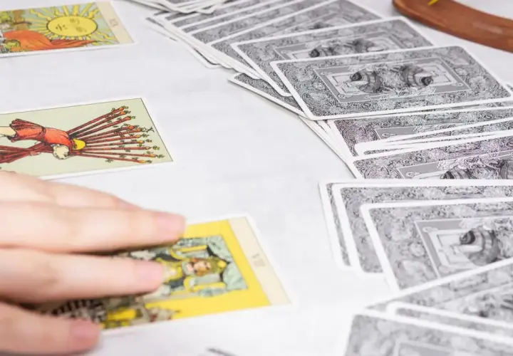 Tarot tygodniowy Skorpion: rozłożone karty tarota, ręka wybiera jedną z nich.