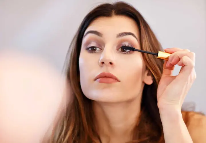 Une femme applique du mascara sur ses cils. Elle apprend comment mettre du mascara pour un regard intense.