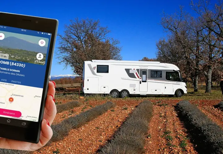 Une application camping-car à la ferme guide vers le Domaine des Oliviers. Un camping-car blanc est garé dans un champ de lavande séchée.