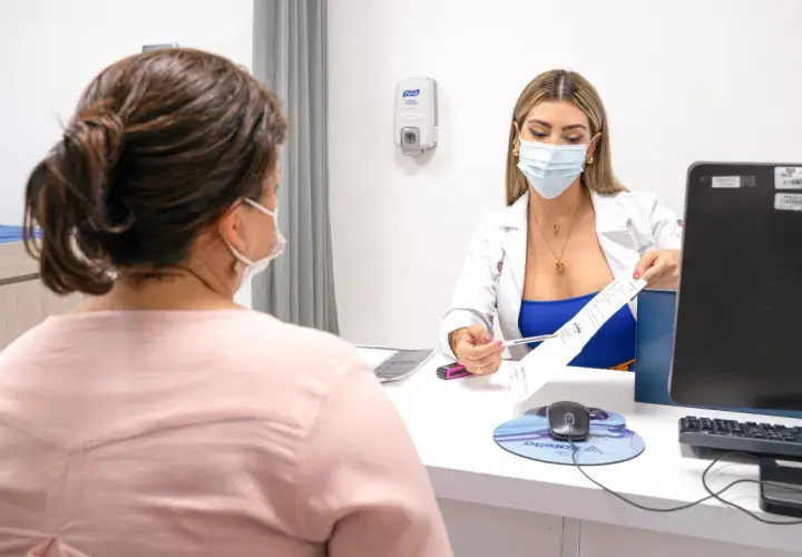 Médica explica tratamiento para la acidez en la boca a paciente.
