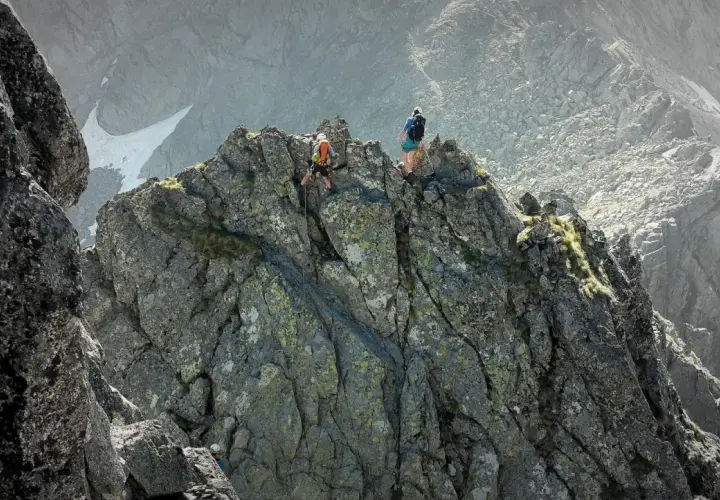 Dwóch alpinistów pokonuje skalisty grzbiet. Jeden z nich schodzi po linie, drugi obserwuje. To trudna droga Martina na Gerlach.