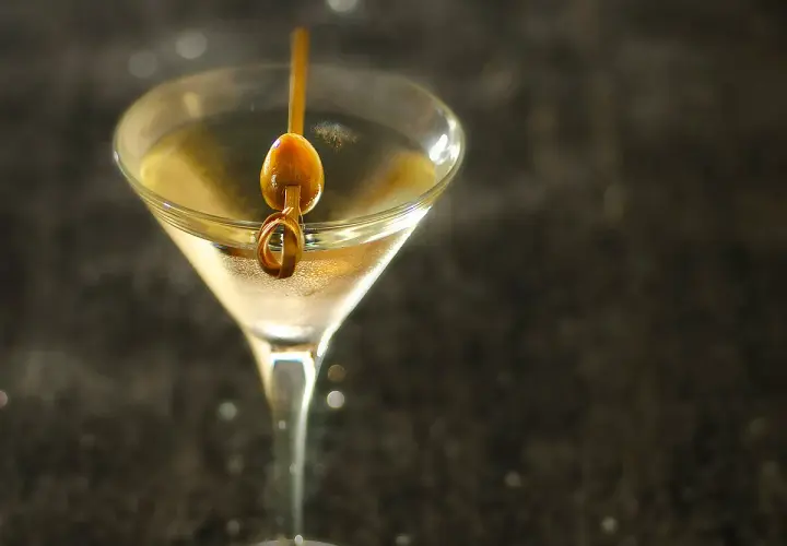 Un verre à martini rempli d'un cocktail clair, garni d'une olive sur un cure-dent. Une image parfaite pour une vodka martini recette.