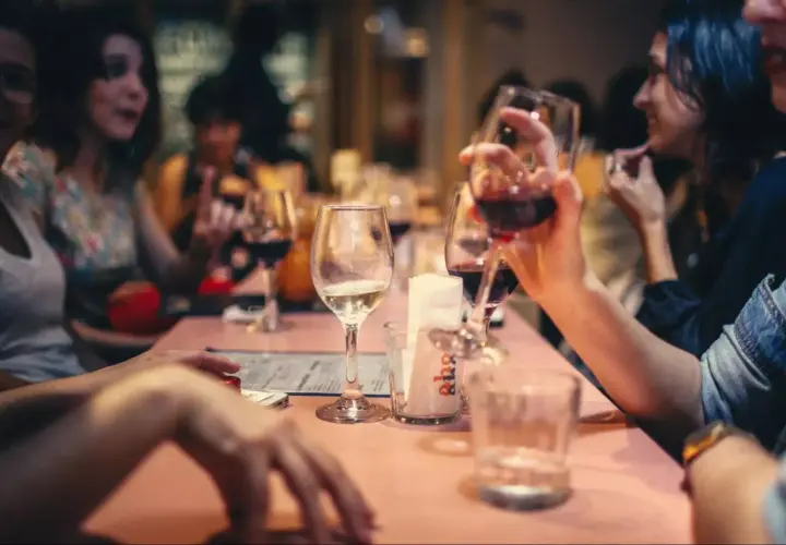 Amis partageant un bon type vin rouge et blanc autour d'une table rose.