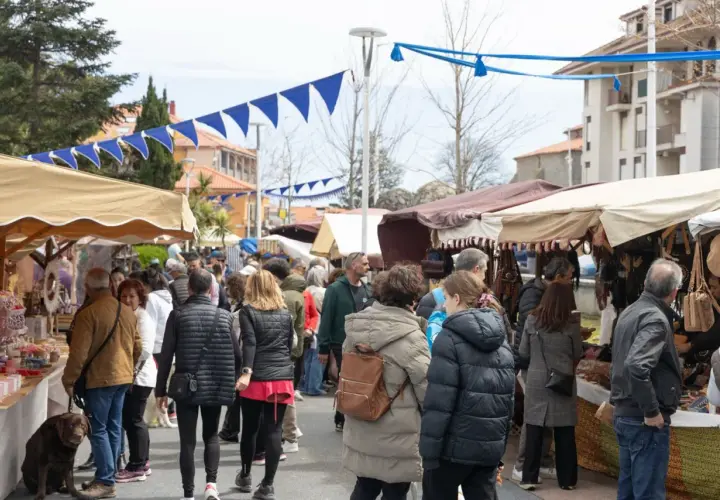 Gente paseando por el mercadillo de Noja, con puestos de artesanía y decoración bajo toldos.