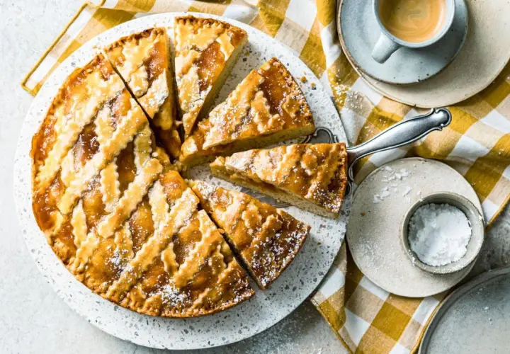 Ein köstliches Crostata-Rezept, aufgeschnitten und mit Puderzucker bestäubt, daneben eine Tasse Espresso.