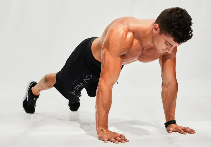 Hombre haciendo flexiones en posición de plancha, listo para un entrenamiento de **hiit en casa**.
