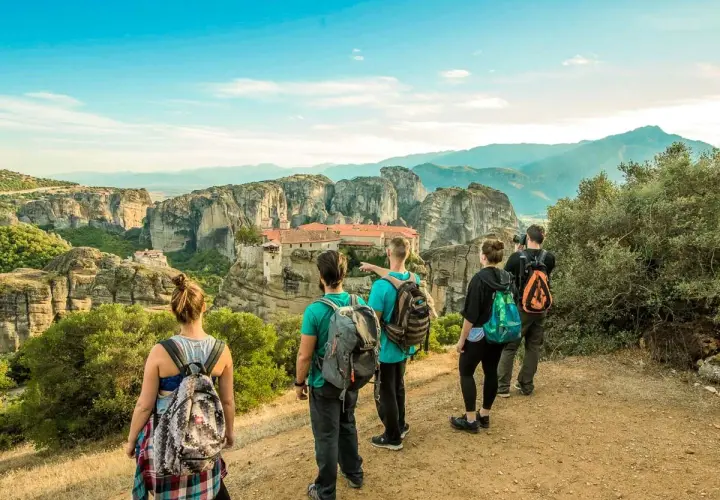 Hikers admire the stunning monasteries of Meteora, Greece, from a scenic viewpoint. The group enjoys a breathtaking vista during their hiking adventure.