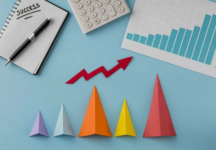 Notatnik z napisem "SUCCESS", kalkulator, wykres słupkowy i czerwona strzałka w górę symbolizują udany marketing performance.