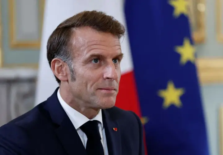 Emmanuel Macron na tle flagi Francji i UE. Czy we Francji jest ta sama godzina co w Polsce? Nie, jest godzina wcześniej.