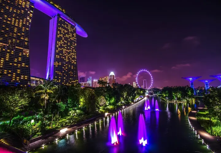 Widok nocny Singapuru z Marina Bay Sands, diabelskim młynem i podświetlanymi drzewami.