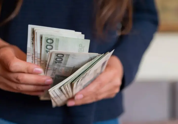 Dłonie liczą banknoty 100 zł. To portierka, która właśnie otrzymała zapłatę za swoją pracę.