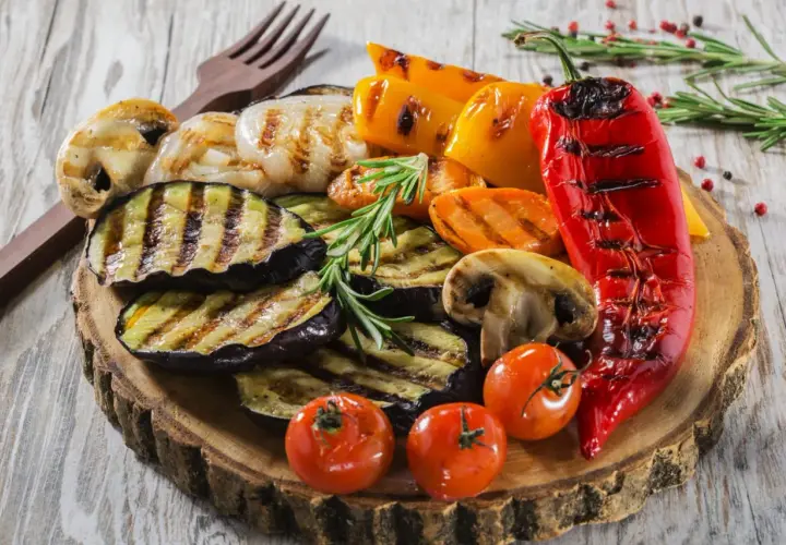 Pyszne przekąski na grilla: grillowany bakłażan, papryka, pieczarki, pomidorki i cebula, udekorowane rozmarynem.