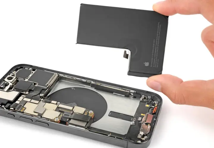 Wymiana baterii w iPhone 16. Dłoń trzyma nową baterię, gotową do montażu w otwartym telefonie.