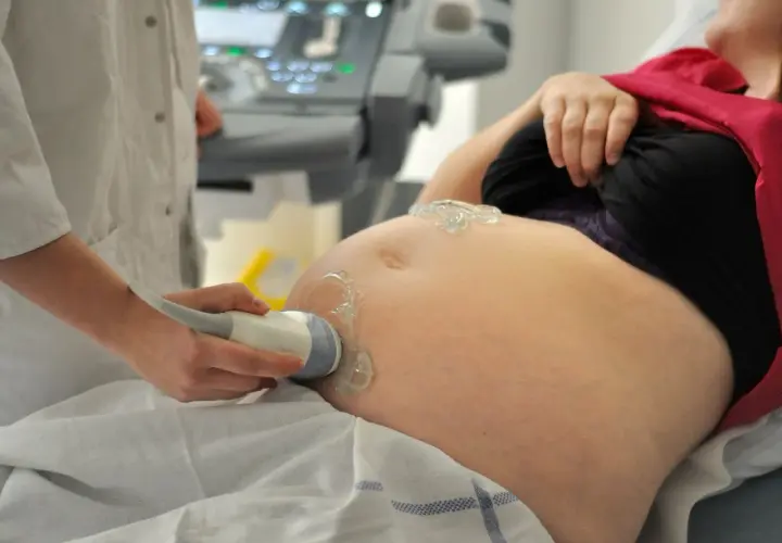 Eine Ärztin führt eine Ultraschalluntersuchung am Bauch einer Schwangeren durch. Die Frage, wie lange dauert eine schwangerschaft, wird hier bildlich beantwortet.