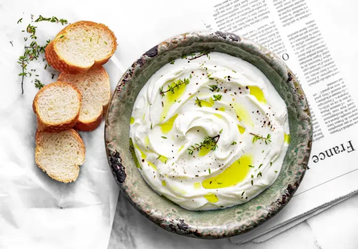 Labneh co to? Kremowy, gęsty serek z jogurtu, polany oliwą i posypany ziołami, podany z chrupiącym pieczywem.