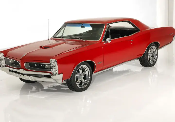 Klasyczny, czerwony Pontiac GTO z chromowanymi felgami, lśniącym lakierem i charakterystyczną atrapą chłodnicy.