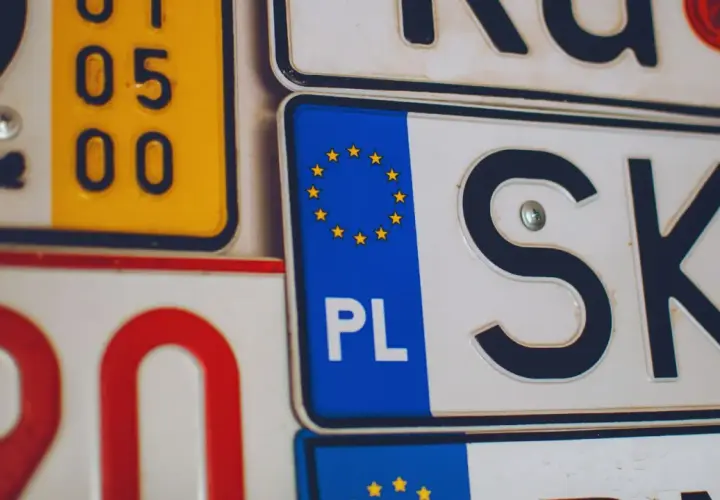 Zbliżenie na tablice rejestracyjne, w tym polskie z symbolem UE i oznaczeniem "PL", a także fragmenty innych tablic.