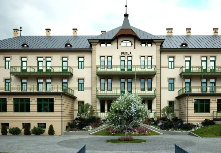 Elegancki budynek DUKLA z zielonymi balkonami i drzewkiem przed wejściem. Sprawdź bardejowskie termy cennik i zaplanuj relaks.