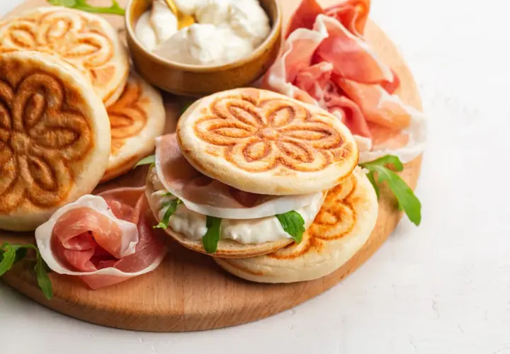 Tavola con crescentine, affettati e formaggio cremoso, un assaggio dei piatti tipici bolognesi.
