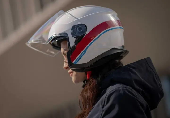 Donna con casco bianco e strisce rosse e blu, un esempio di diversi tipi di casco per la sicurezza in moto.