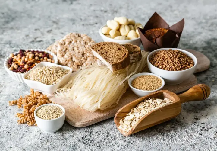 Różnorodne produkty spożywcze, w tym ryż, makaron ryżowy, kasza, płatki owsiane, chleb, ciastko i nasiona.