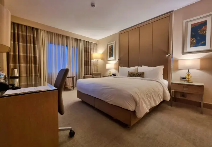 Komfortowy pokój hotelowy, idealny po długim locie tureckimi liniami lotniczymi. Duże łóżko, biurko i przytulne oświetlenie.