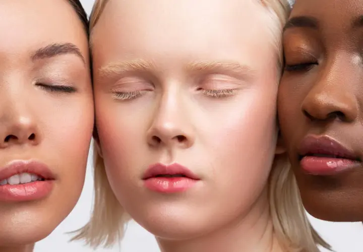Trois visages aux teints variés, aux yeux clos, sublimés par un maquillage discret et naturel.