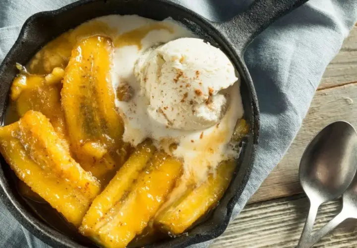 Banane flambée servie dans une poêle en fonte, nappée de glace à la vanille et saupoudrée de cannelle. Un délice gourmand.