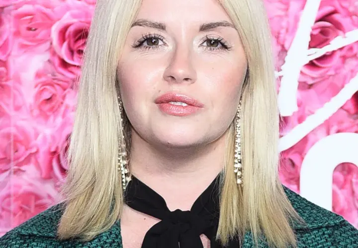 Agnieszka Wolszczyk, wiek nieznany, na tle różowych róż. Długie blond włosy, błyszczące kolczyki.