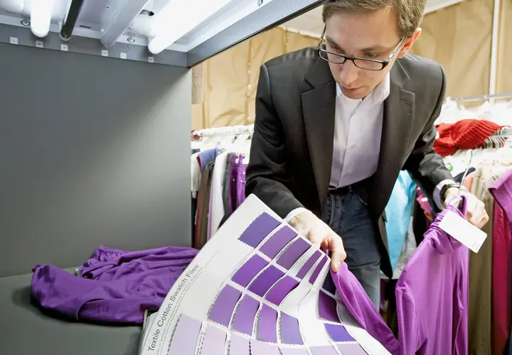 Un ingénieur textile examine des échantillons de couleurs violettes, comparant une chemise à un nuancier.