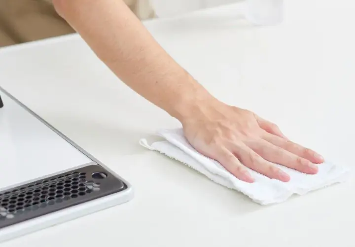 Mano limpiando una superficie blanca con un paño, como si fuera limpiar suelo de mármol.