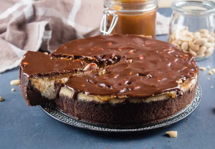 Gâteau façon Snickers, avec une base chocolatée, une couche crémeuse, du caramel coulant et une ganache au chocolat parsemée de cacahuètes. Un délice !