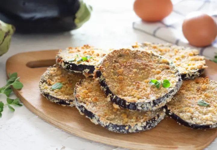 Cotolette di melanzane dorate e croccanti, guarnite con erbe aromatiche fresche, pronte per essere gustate.