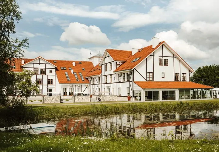 Malowniczy widok na narie resort & spa z łódką przy brzegu i odbiciem w wodzie.