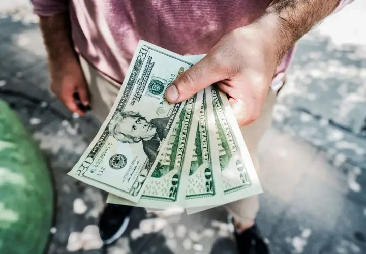 Dłoń trzyma kilka banknotów po 20 dolarów. Zastanawiasz się, skąd wziąć kasę na spełnienie marzeń?